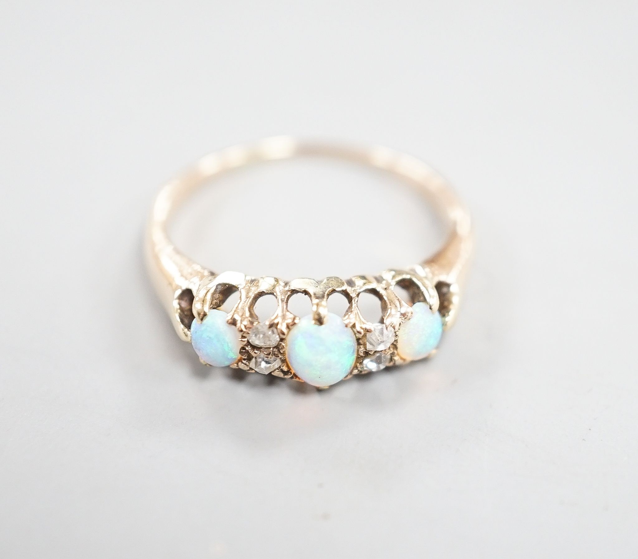 An early 20th century yellow metal three stone white opal and four stone diamond chip set half hoop ring, size M, gross weight 2.6 grams.